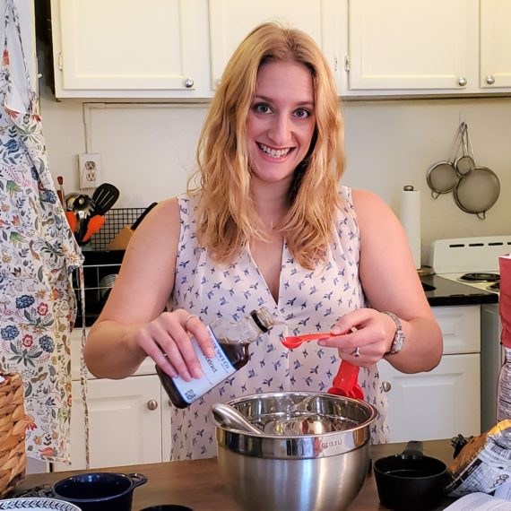 joey rockman in her kitchen pouring out vanilla extract surrounded by baking ingredients